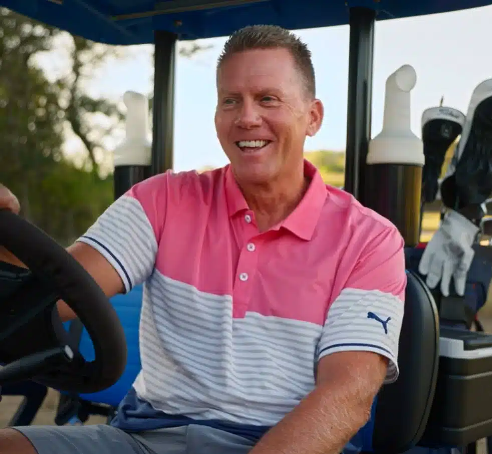resident driving golf cart at kissing tree