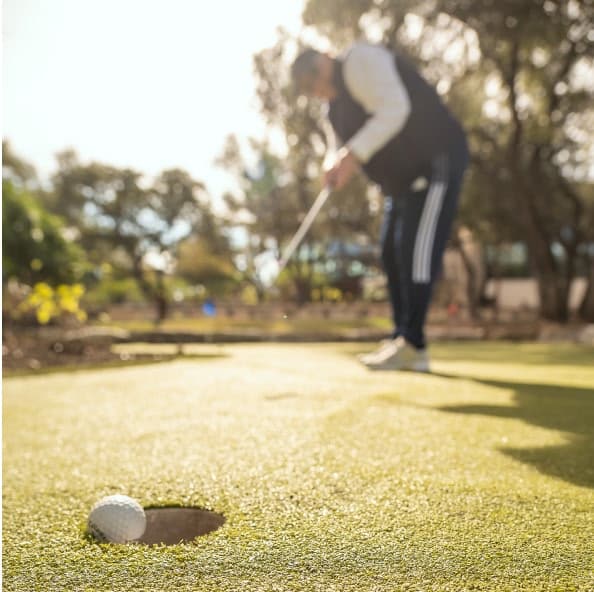 person practicing putting with ball going in hole