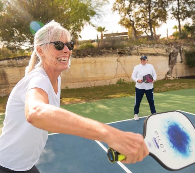 person playing pickleball at kissing tree