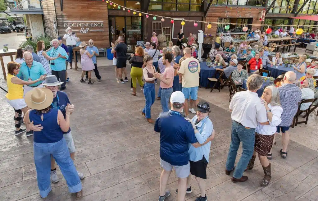 Kissing Tree neighbors dancing at an outdoor community event at Independence Hall in San Marcos, Texas