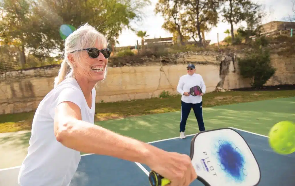 Kissing Tree resident playing pickleball on the community courts, part of the active adult lifestyle in San Marcos, Texas