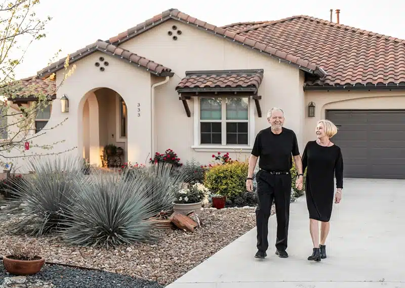 couple standing in front of new home at kissing tree